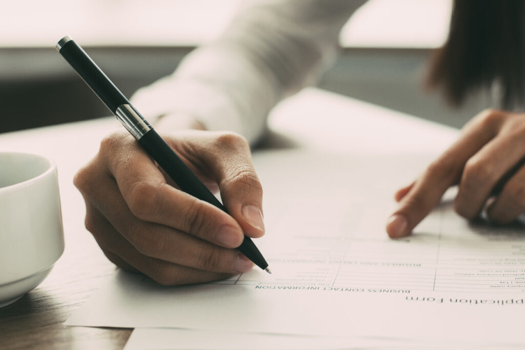 Femme rédigeant une lettre de motivation et remplissant un formulaire de candidature à domicile
